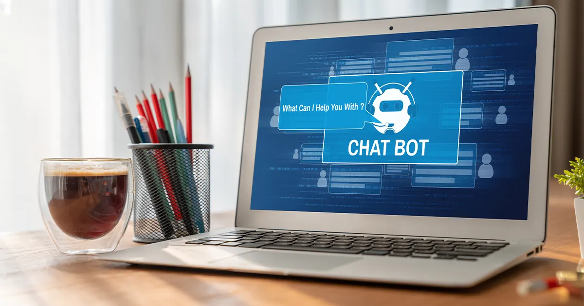 Das Bild zeigt einen Computer, der auf einem Schreibtisch steht. Auf dem Bildschirm ist ein Chatbot.